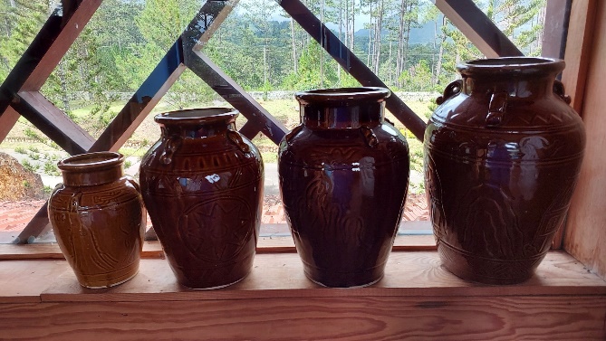 A group of brown vases on a shelfDescription automatically generated